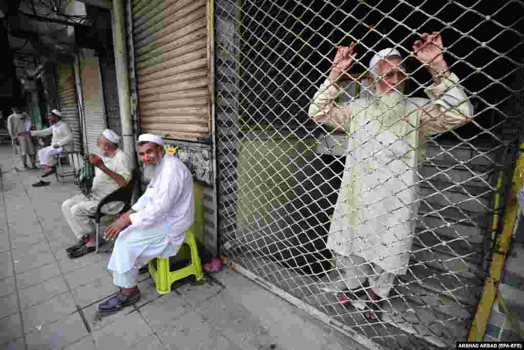Men wait near currency exchange shops in Peshawar on September 8, following their closure by the government. The devaluation of the Pakistani rupee, along with soaring inflation, critically low foreign reserves, and rising fuel prices, has brought significant hardships to the country&#39;s citizens and placed considerable strain on the cash-strapped caretaker government.