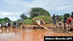 Stanovnici sela Chamwana Muma u Keniji nakon što se urušio improvizovani most preko nabujale reke Tana u Keniji, 15. novembar 2023.
