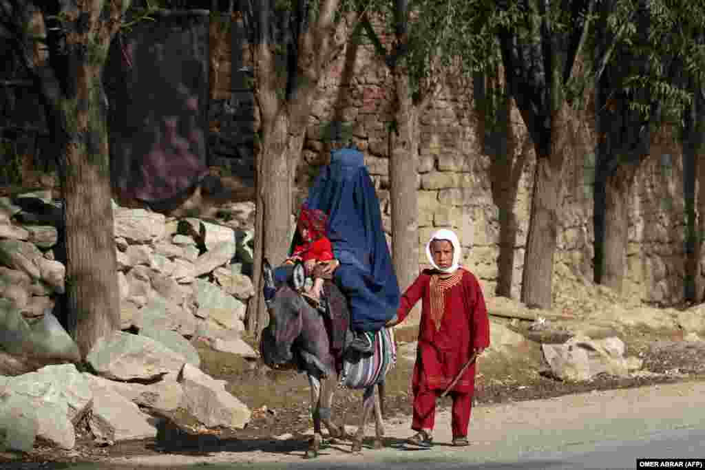 An Afghan woman rides a donkey along with her children on a street in the Tagab district of northeastern Badakhshan Province.
