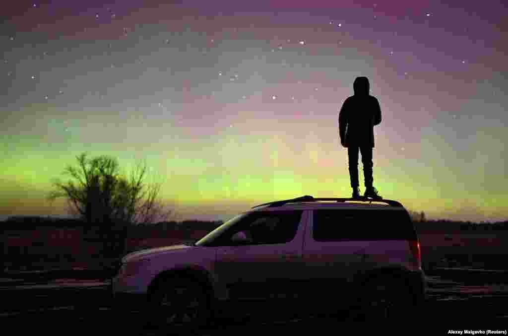 A person stands on a car while looking at an aurora borealis in Russia&#39;s southwestern Omsk region in Siberia.&nbsp;