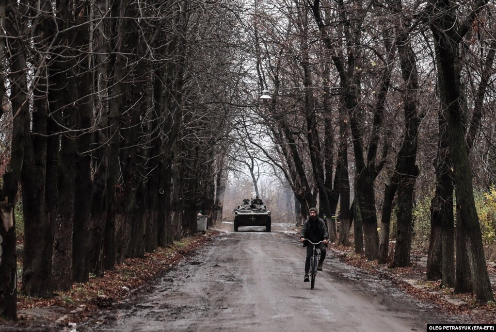 Një burrë duke lëvizuar me biçikletë ndërsa një automjet ushtarak i këmbësorisë kalon nëpër qytetin e Çasiv Jar, pranë vijës së frontit në rajonin e Donjeckut të Ukrainës.