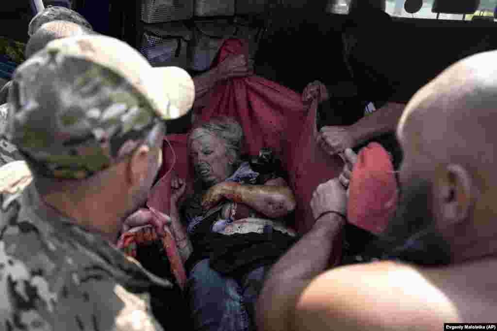 Ukrainian soldiers move an injured woman to an ambulance.