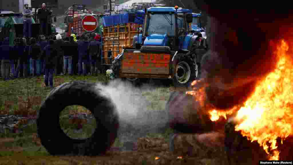 Francia gazdák felgyújtott gumiabroncsok&nbsp; és &bdquo;Ez értelmetlen&rdquo; feliratú mezőgazdasági jármű mellett 2024. január 24-én&nbsp;Bretagne-ban