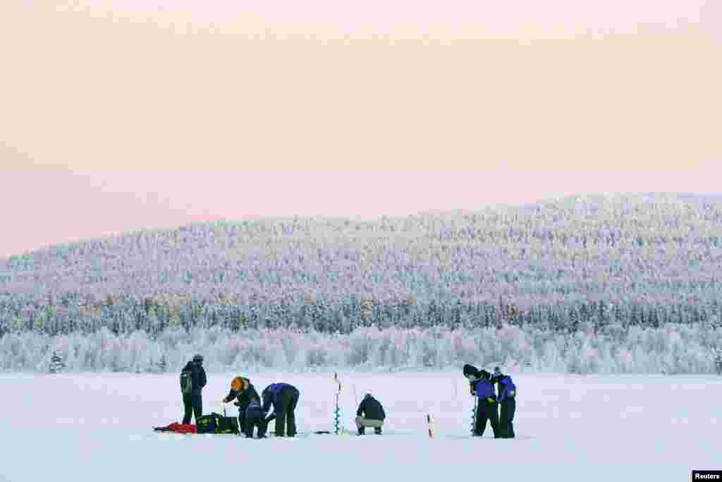 Njerëzit duke zënë peshq nën akull në qytetin e Akaslompolos, në Kolari, Finlandë, 4 janar 2024.