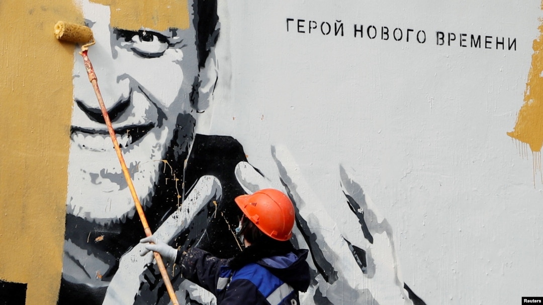 Un muncitor din Sankt Petersburg șterge o pictură murală care îl înfățișează pe politicianul rus de opoziție Aleksei Navalny, întemnițat în aprilie 2021. Pe zid scrie: „Eroul noii ere”.