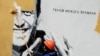 Работник заличава с боя графит, изобразяващ руския опозиционер Алексей Навални, в Санкт Петербург, Русия, 28 април 2021 г. Графитът гласи: "Герой на новото време".