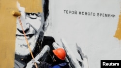 Radnik u Sankt Peterburgu prefarbava mural koji prikazuje zatvorenog ruskog opozicionog političara Alekseija Navaljnog u aprilu 2021. Na muralu piše: "Heroj novog vremena". 