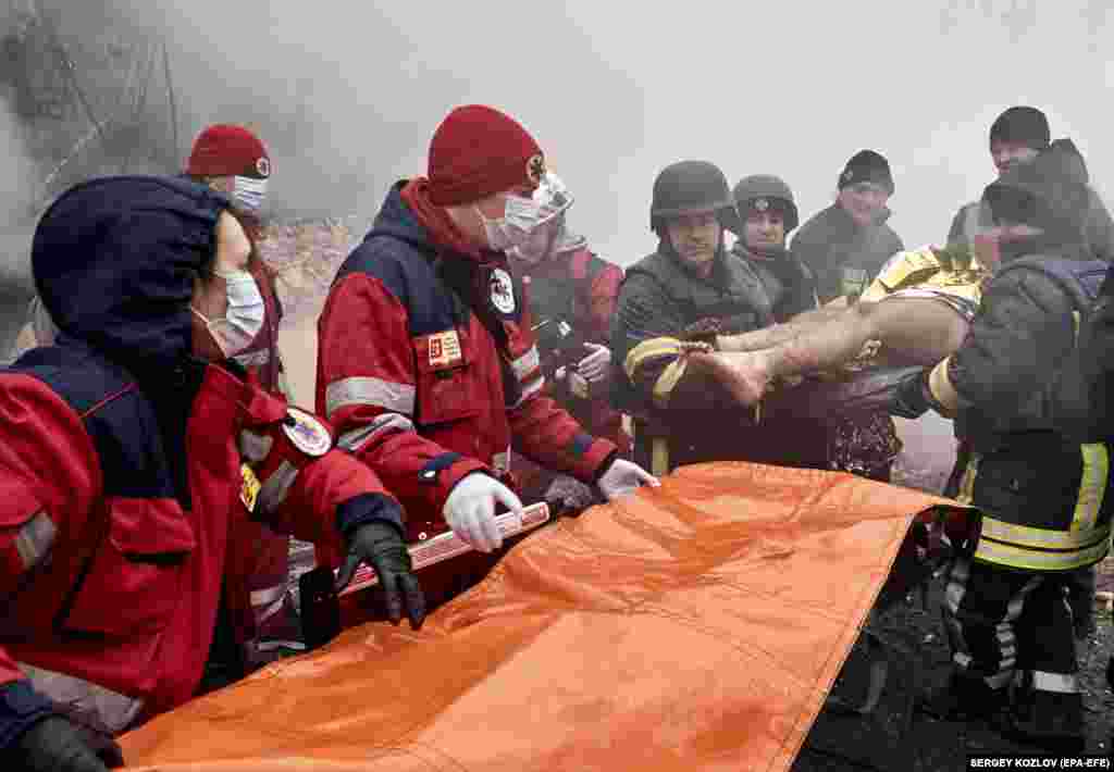 Рятувальники надають допомогу постраждалому чоловіку, який понад 5 годин пролежав під завалами на місці ракетного обстрілу житлового будинку в Харкові