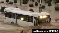 Автобус передвигается в скопившейся на дороге дождевой воде. Ашхабад. Май 16, 2024. 