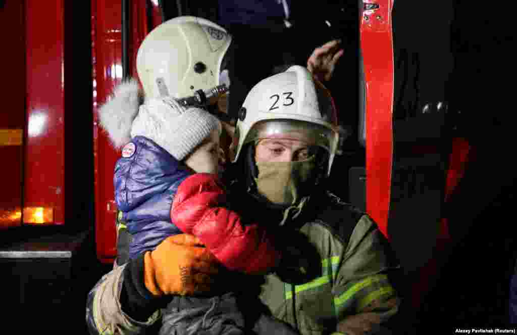 Спасатель несет ребенка, пока местные жители выходят из грузовика во время экстренной эвакуации с затопленной улицы в Евпатории