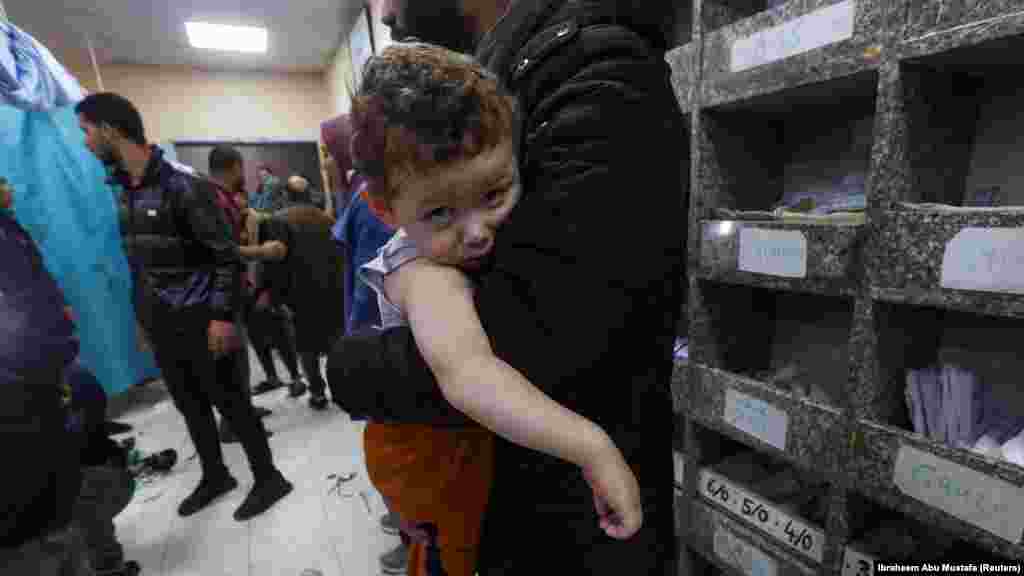 Palesztin gyermek édesapja karjában a hán júniszi&nbsp;Nasszer kórházban, 2023. december 5-én. A jelentések szerint&nbsp;izraeli légicsapások érték a helyi iskolát, ahol az emberek menedéket kerestek&nbsp;