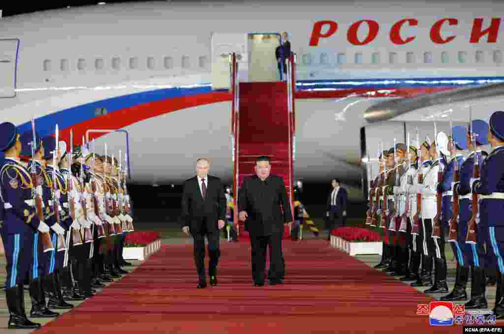 An official photo released by the North Korean Central New Agency (KCNA) shows Putin (left) walking with North Korea&#39;s Kim upon his arrival at the airport in Pyongyang. State television showed Kim and Putin shaking hands and repeatedly hugging on the Russian leader&#39;s predawn arrival at Pyongyang airport.