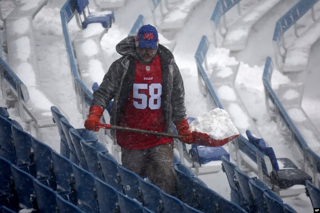 Një punëtor ndihmon për të hequr borën nga stadiumi Highmark në Nju Jork.