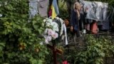 60-летняя Ирина смотрит на могилу сына Романа. Он похоронен в саду возле дома в селе Долгенькое на востоке Украины. Роман погиб в результате российского обстрела. Ему было 39 лет