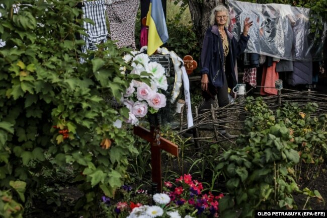 Iryna, 60 vjeçe, shikon varrin e të birit, Romanit, i cili ndodhet në oborrin e shtëpisë së saj, në fshatin Dovhenke, në Ukrainën lindore. Djali i saj ishte 39-vjeçar kur u vra nga bombardimet ruse.