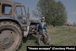 Николай Трищенко возле своего трактора. Это единственная работающая техника, которая осталась в деревне. Фото: Наталья Лозинская для НВ