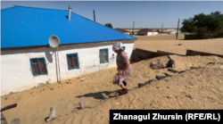 Zhenis Mamyrova walks over the sand-covered outbuilding immediately behind her house.