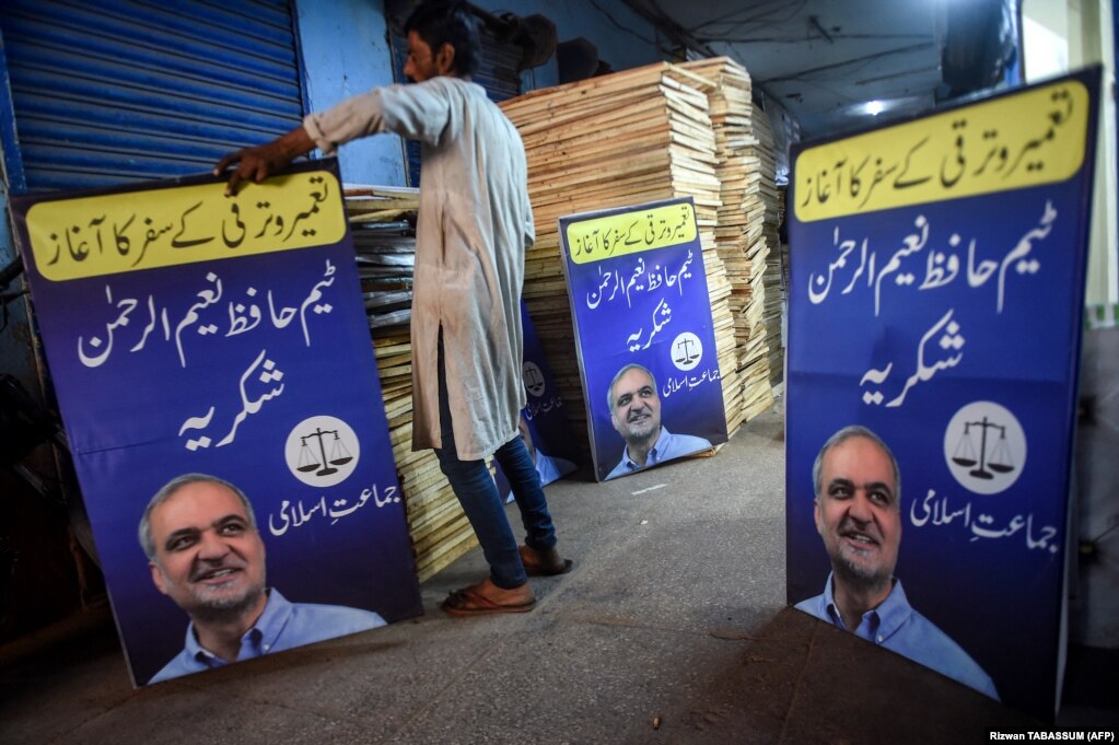 Një punëtor duke rregulluar posterë të partisë Jamaat-e Islami (JI) në Karaçi, me liderin e tyre Hafiz Naeem ur-Rehman dhe simbolin e partisë - një peshore.