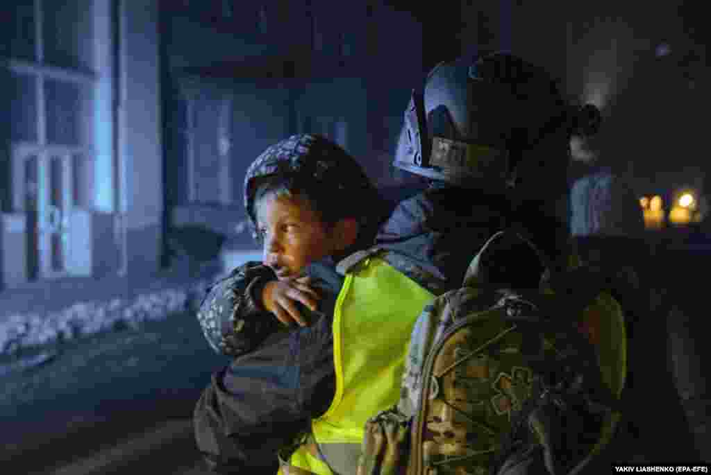 A police officer carries a boy at the site of a Russian rocket attack in Kharkiv.