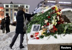 O femeie depune flori la monumentul dedicat victimelor represiunilor politice după moartea liderului opoziției ruse Alexei Navalnîi la Moscova, 16 februarie 2024.