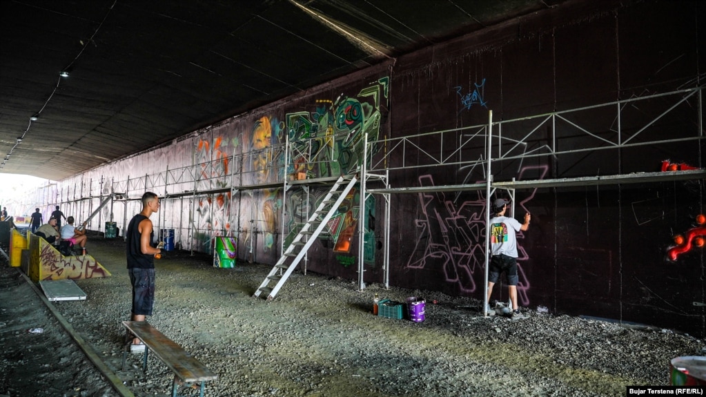 Artistët duke punuar në muret e tunelit të hekurudhës, pranë Stacionit të Trenave.&nbsp;