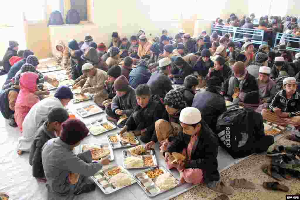 Orphaned Afghan children eat together at an orphanage in Kandahar operated by the Department of Labor and Social Affairs. Officials have gathered children who used to collect alms in the city and are now nurturing around 350 orphans, as well as children of disabled and drug-addicted parents.