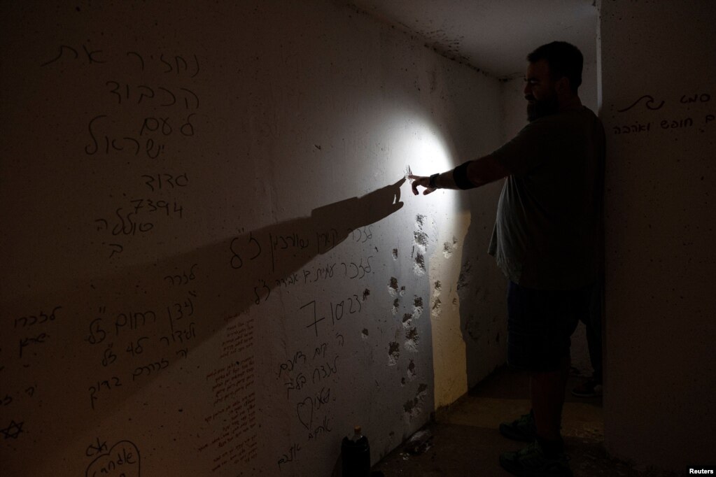 Një burrë prek një të çarë të krijuar në murin e një strehimoreje që u sulmua nga Hamasi, afër kufirit me Gazën.