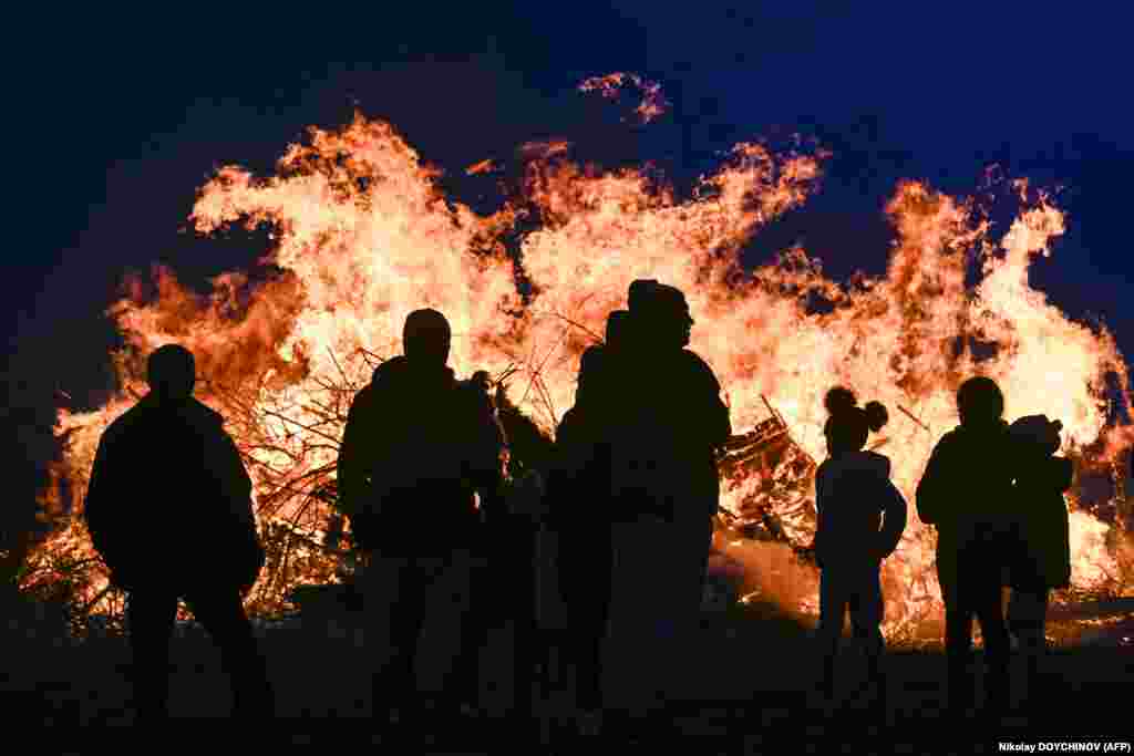 Revelers look at a bonfire as Bulgarians celebrate Mesni Zagovezni, an Orthodox Christian holiday during which they chase away evil spirits with fire rituals, in the village of Lozen.