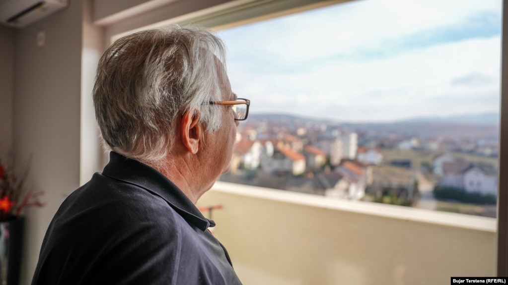 Palokë Berishaj duke shikuar nga dritarja e banesës së tij në Prishtinë.