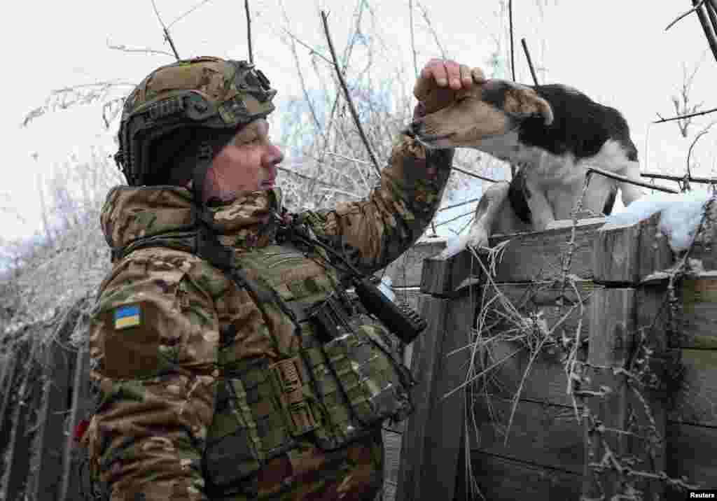 Artem, një ushtar i batalionit të këmbësorisë, brigada e 61-të e mekanizuar, përkëdhel një qen në një llogore afër vijës së frontit në rajonin e Harkivit, Ukrainë, 6 janar 2024.