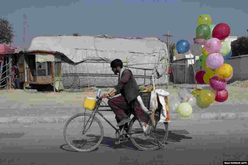 An Afghan balloon vendor rides a bicycle along a street in Kabul.