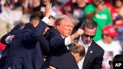 Donald Trump, candidatul republican la președinție, evacuat de pe scenă după ce a fost atins de un glonț la ureche, în timpul unei întâlniri electorale la Butler Farm Show, în Pennsylvania, pe 13 iulie 2024.