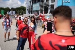 Një tifoz shqiptar dhe një tifoze kroate, të veshur me ngjyrat e flamujve të kombëtareve të veta, bëjnë një fotografi së bashku jashtë stadiumit, para ndeshjes Shqipëri - Kroaci. (Foto: AFP)
