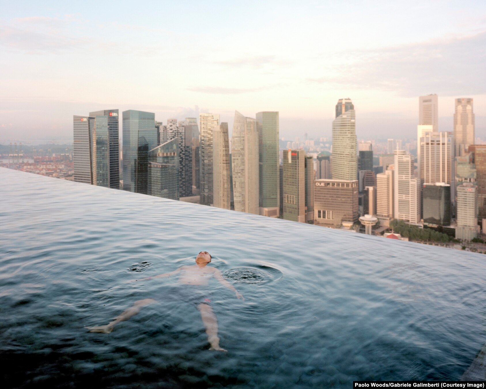 Një burrë duke notuar në një pishinë në katin e 57-të në hotelin Marina Bay Sands. Në prapavijë shihet objekti i qendrës financiare të Singaporit.