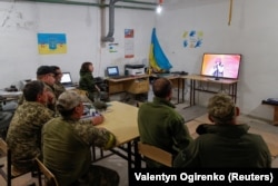 Ukrainian soldiers watch the Ukrainian group Kalush Orchestra perform in the final of the 2022 Eurovision Song Contest, from their position in the Kyiv region on May 14, 2022.