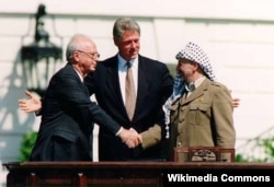 Історичне рукостискання прем’єр-міністра Ізраїлю Іцхака Рабина (ліворуч) і глави Організації визволення Палестини Ясіра Арафата (праворуч) у присутності президента США Білла Клінтона. Вашингтон, США, 1993 рік