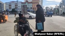یک مرد کهنسال و معلول که در هرات روی جاده ها کارت های موبایل می فروشد