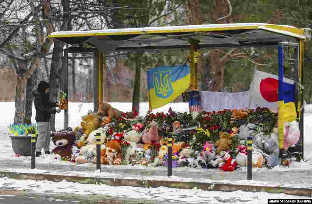 Ukrajinci odaju počast žrtvama na autobuskoj stanici u blizini ruševina stambene zgrade uništene u raketnom udaru u Dnjepru, na jugu Ukrajine.