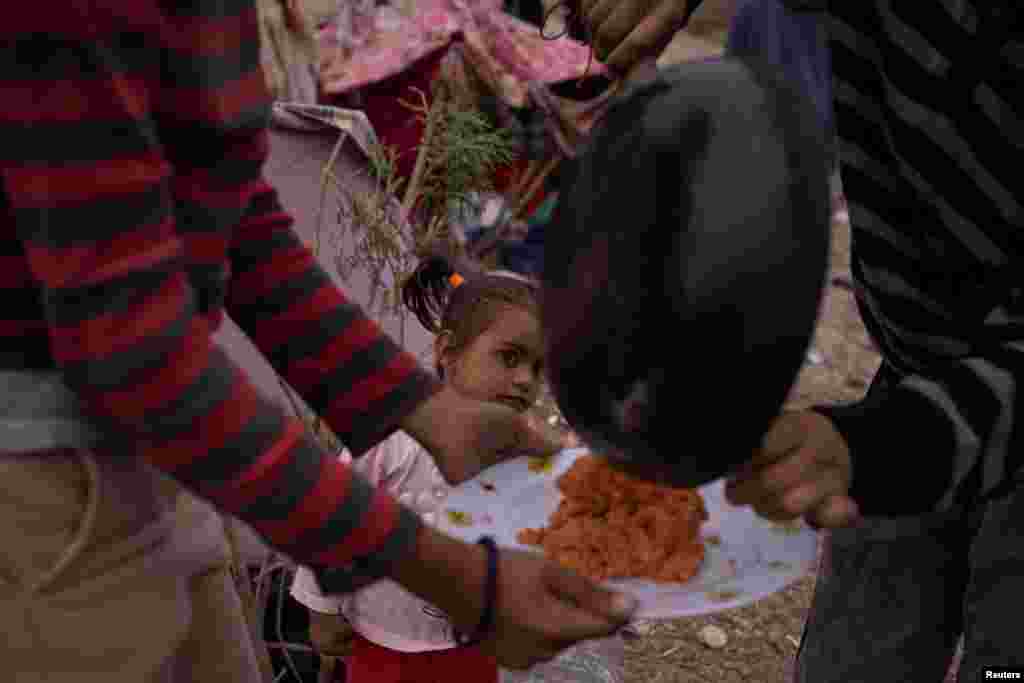 Susej, një vajzë dyvjeçare emigrante nga Venezuela, shikon vezët që familja e saj përgatit për darkën e tyre teksa ata kalojnë netët përgjatë bregut të lumit Rio Grande ndërsa presin t&#39;u dorëzohen autoriteteve të imigracionit në El Paso, Teksas, Shtetet e Bashkuara të Amerikës, 23 mars 2024.