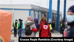 Un voluntar Crucea Roșie întâmpină refugiați ucraineni la granița cu România (2022).