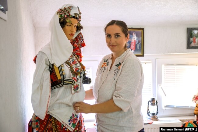 Arbnora Kolgjeraj Rexha duke e veshur një manekine me rroba tradicionale.