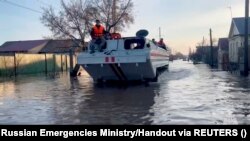 Salvatorii caută rezidenți pe care să îi evacueze în timp ce circulă într-o zonă rezidențială inundată din orașul Orsk, Rusia, 6 aprilie 2024.