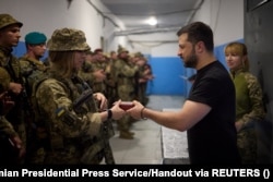 Ukrainian President Volodymyr Zelenskiy awards a Ukrainian soldier as he visits a position at a front line in the Donetsk region on September 4.