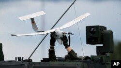 Vojnik drži dron na vrhu vojnog vozila NATO-a na vojnoj vježbi u Pabradeu, Litvanija, 26. juna 2023.