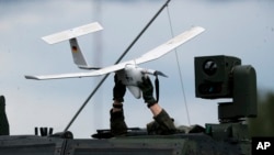 A soldier holds a drone over a NATO military vehicle during a military exercise in Lithuania in June 2023.