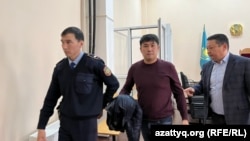 Аслана Утепова (в центре) выводят из зала суда. С конца декабря он содержится под стражей. Уральск, 24 марта 2023 года