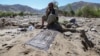 A man affected by floods sits next to a prayer mat as he waits for relief in the village of Borka in Baghlan Province in May.