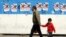 A man and a child walk past campaign posters of parliamentary candidates during the first day of the election campaign in Tehran on February 22.