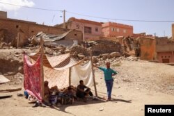 Үйү кыйрагандар колдо бар кездемелерин чатыр кылып отурушат. Амизмиз айылы, Марокко.