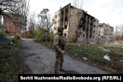 Украинский военный на фоне разрушенных в результате обстрелов жилых домов. Авдеевка, ноябрь 2023 года